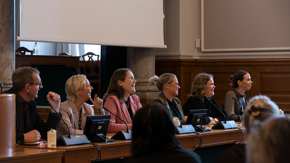 Seks mænd og kvinder ved siden af hinanden ved en paneldebat på Christiansborg